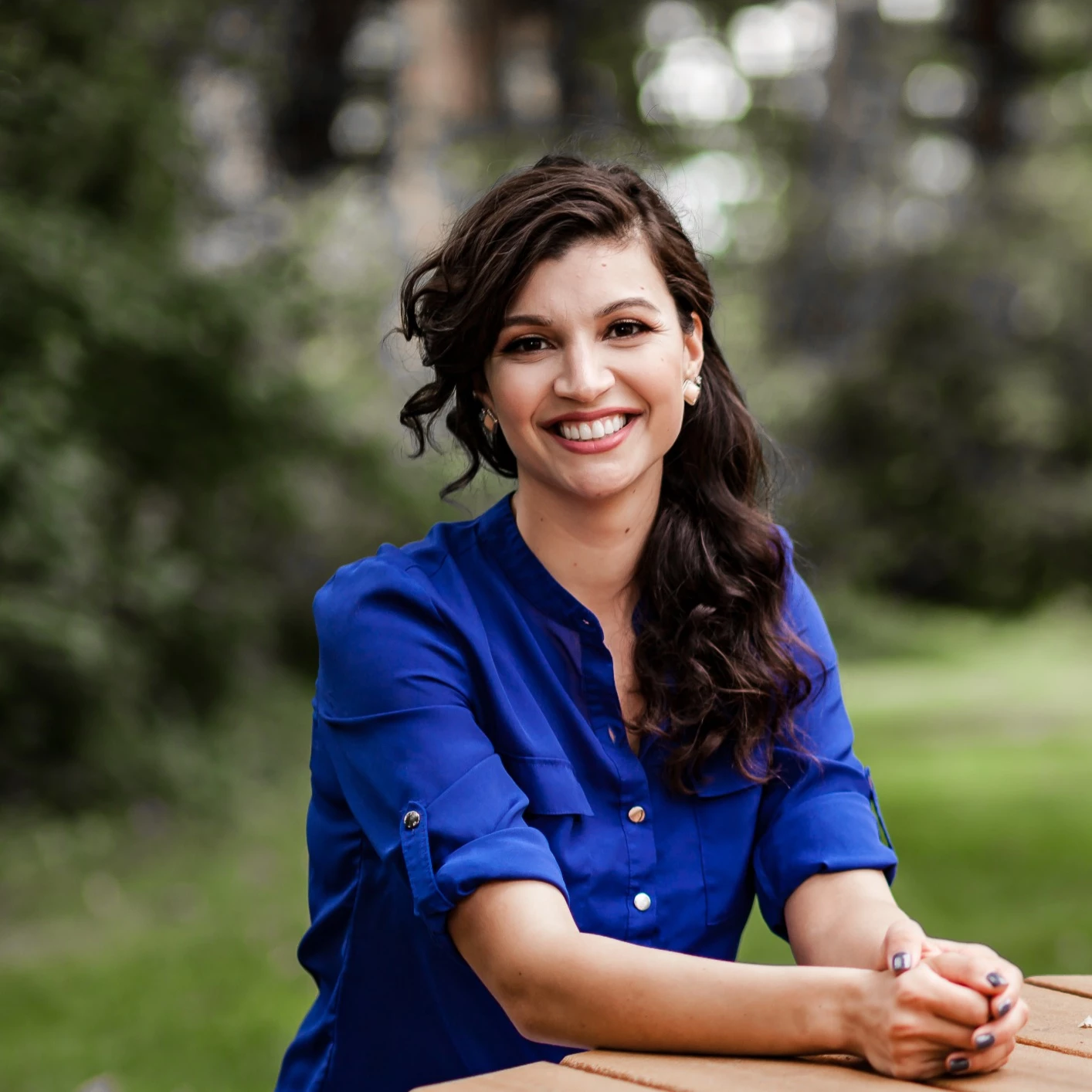 Photo of Sharlett Mena. She is smiling, has long brown hair and is wearing a blue blouse. 